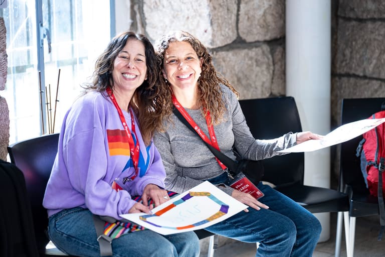 Two mothers smiling with the challah covers they painted