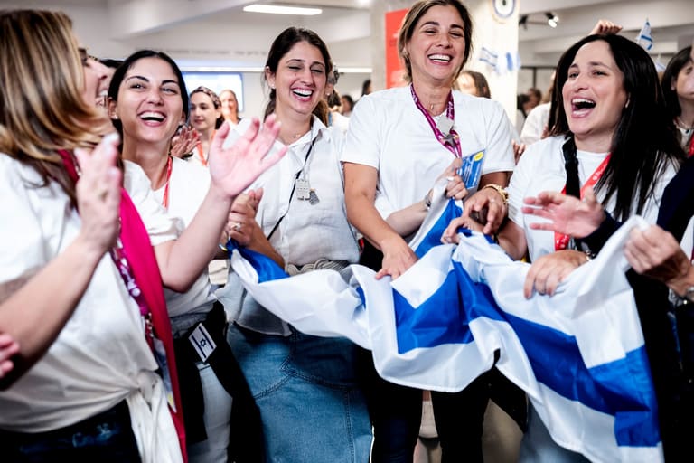 Mothers in white clapping and dancing with an Israeli flag