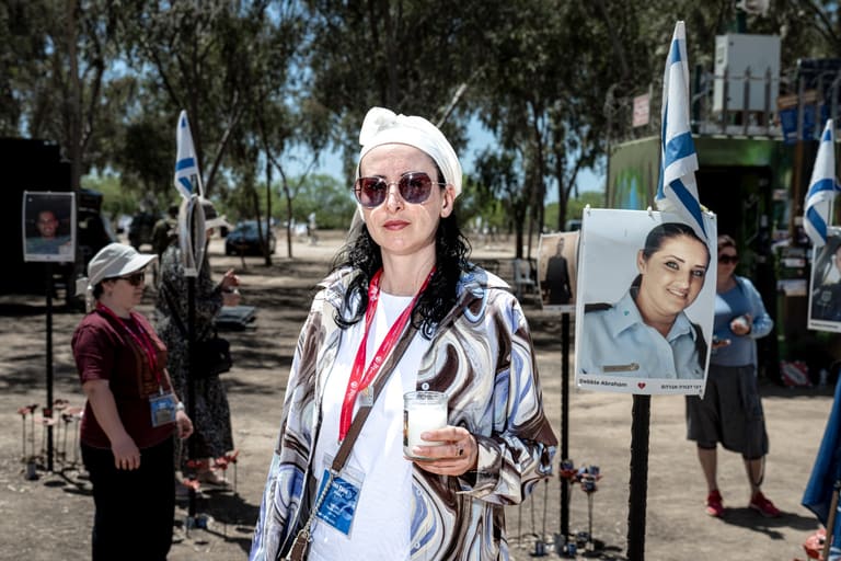 A mother holding a memorial candle among the portraits at the Nova festival site