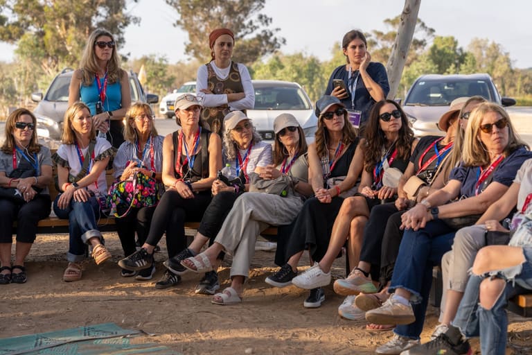 Mothers seated together listening at an outdoor memorial site at golden hour
